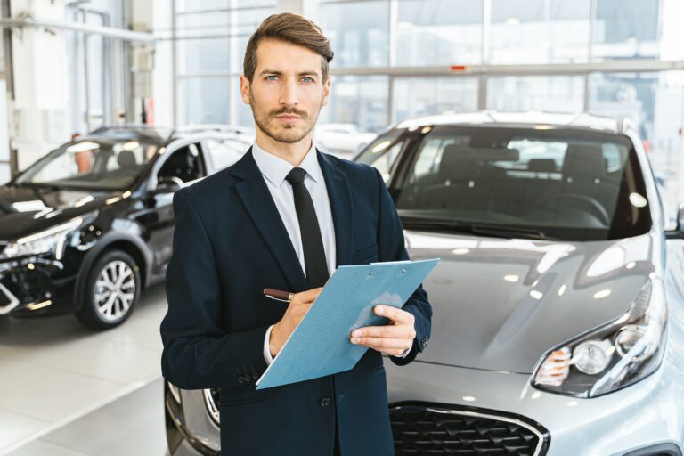 impatient car salesman stands in front of car